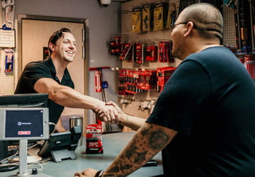 Walk-In & Specialty Smiling employee at a plumbing service counter shaking hands with a contractor