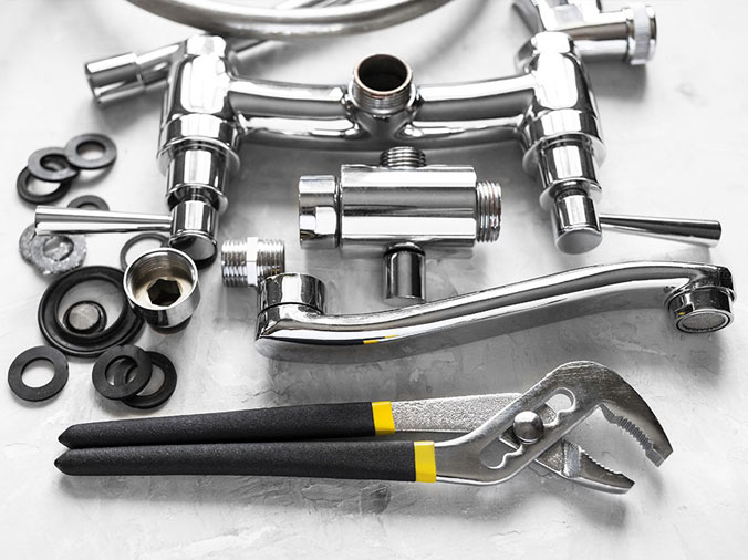 disassembled chrome kithen sink faucet and plumbing plyers